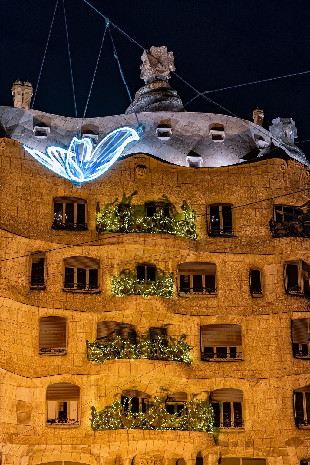Casa Milà il·luminada i amb llums de Nadal a les baranes de ferro forjat dels balcons al passeig de Gràcia, que està decorat amb tires de llums amb papallones volant
