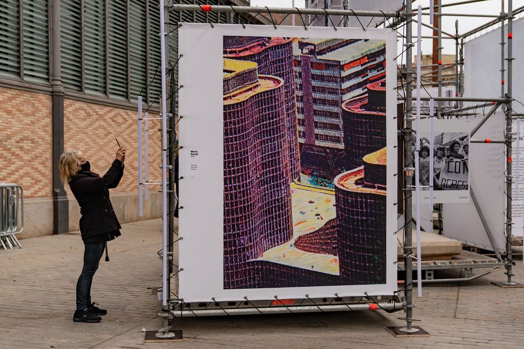 Una visitant fa una fotografia amb el mòbil d'una de les imatges de l'exposició "Barcelona fotògrafes" a l'exterior del CCM El Born