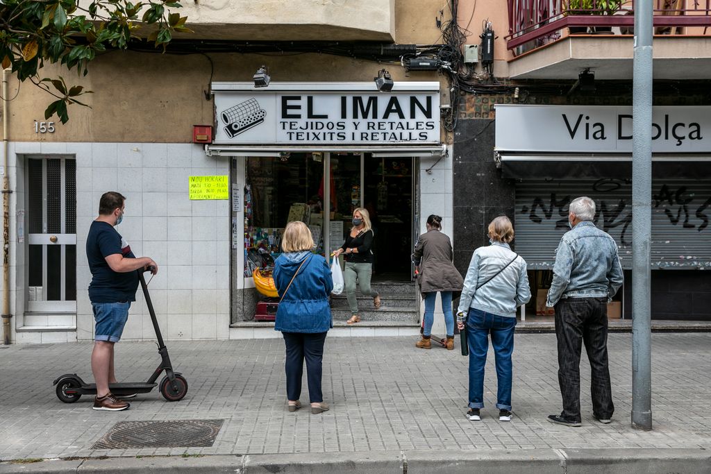 Un grup de persones fan cua guardant les distàncies davant d'una botiga de teixits a la via Júlia