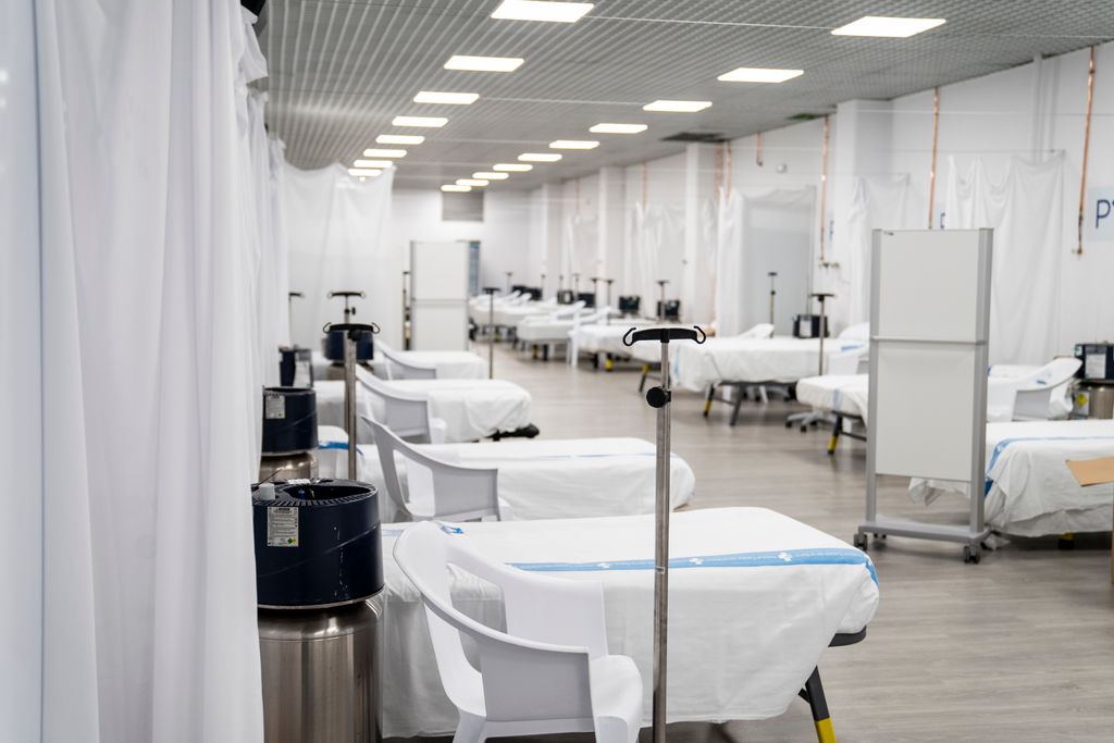 Sala del Pavelló Salut Vall d’Hebron amb llits, bases per a bosses de sèrum i medicació i separadors de cortina