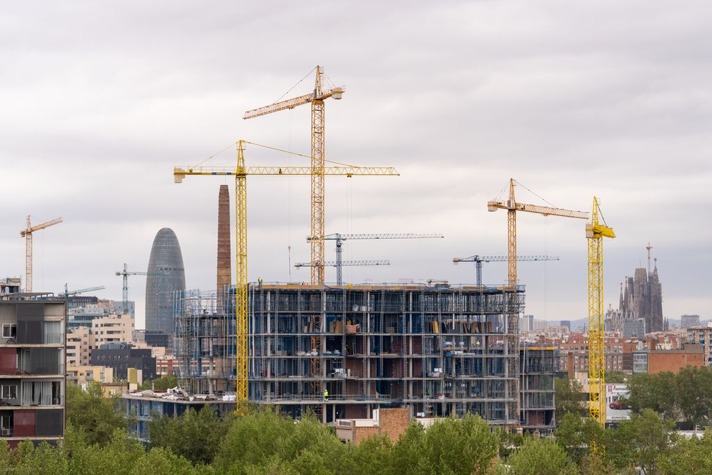 Grues treballant i construint edificis al barri de Provençals del Poblenou amb la Sagrada Família i la Torre Glòries al fons