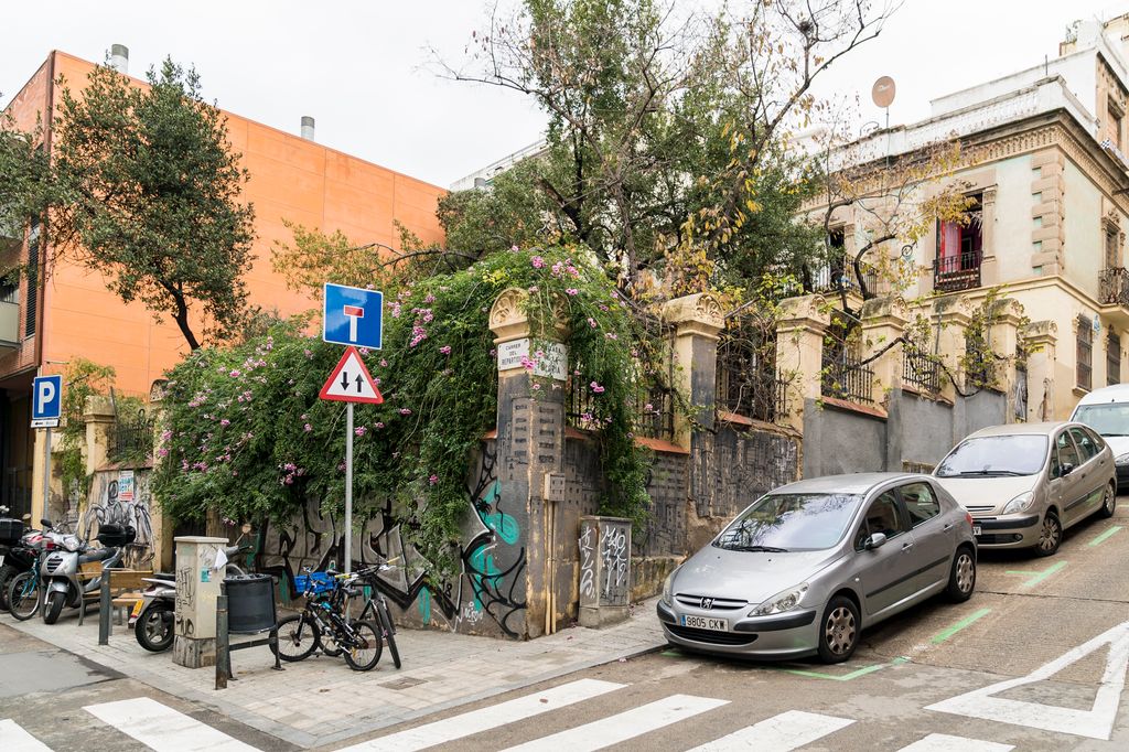 Edifici envoltat per un mur vist des de la cantonada del carrer del Repartidor amb la Baixada de la Glòria