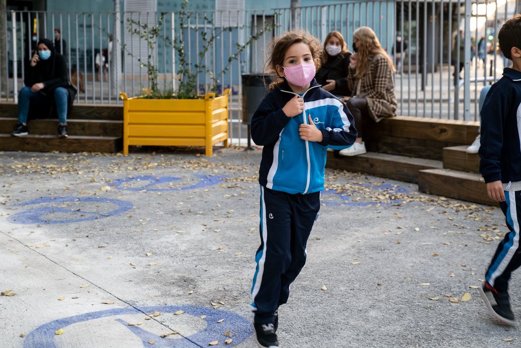 Nena corrent a la zona pacificada de vorera ampliada del Col·legi Escolàpies de Llúria. Al darrere es veu com l’àrea està separada del trànsit del carrer d’Aragó per unes tanques, bancs amb forma d’esglaons de fusta i unes jardineres