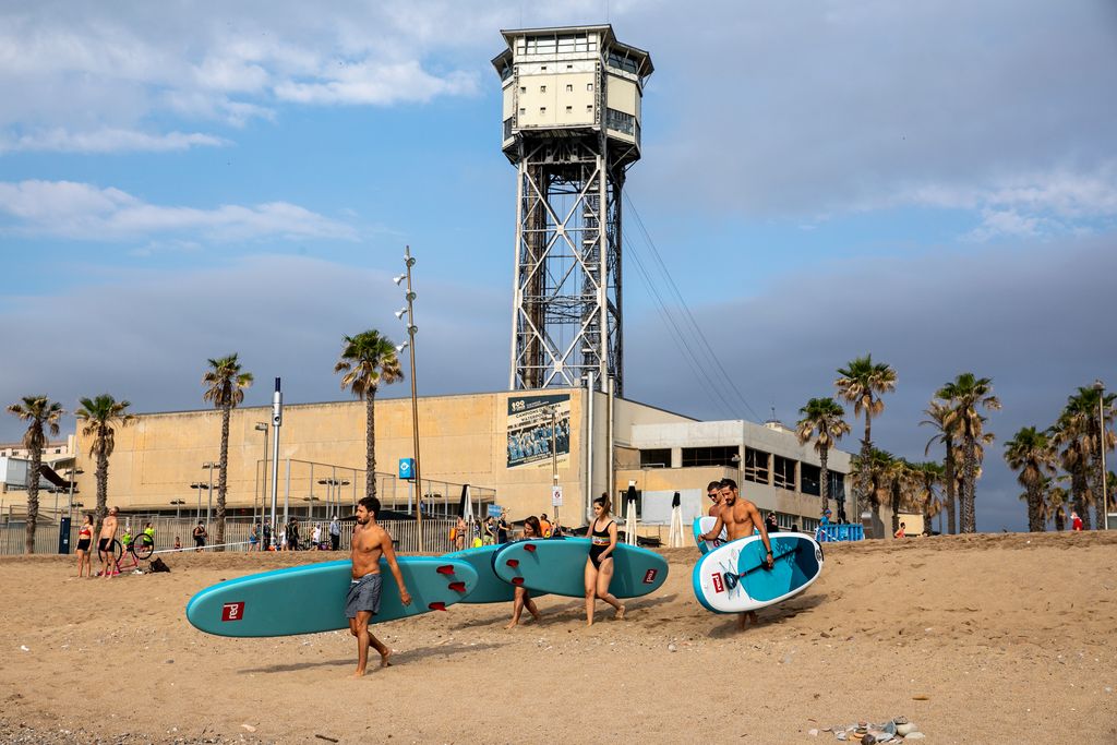 Grup de persones dirigint-se a l'aigua amb les taules i rems per fer surf de rem