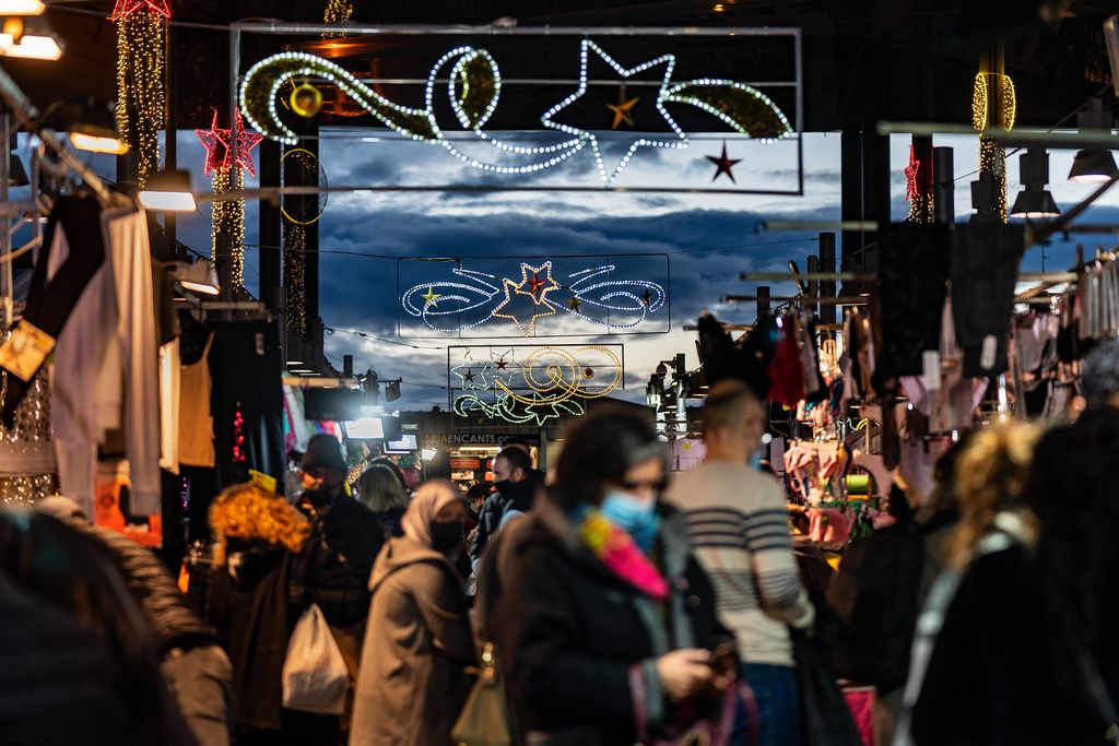 Gent comprant al capvespre al Mercat dels Encants, quan els llums de Nadal de l’equipament es comencen a encendre