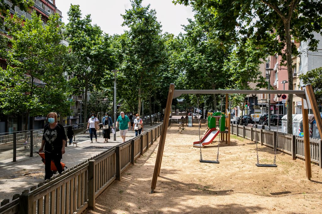 Zona de jocs infantils de la via Júlia tancada. Pel costat passa gent passejant i amb carrets de la compra