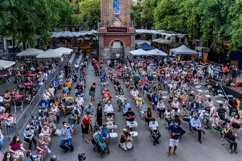 Veïns de Gràcia asseguts a la plaça de la Vila per escoltar el pregó de la festa major
