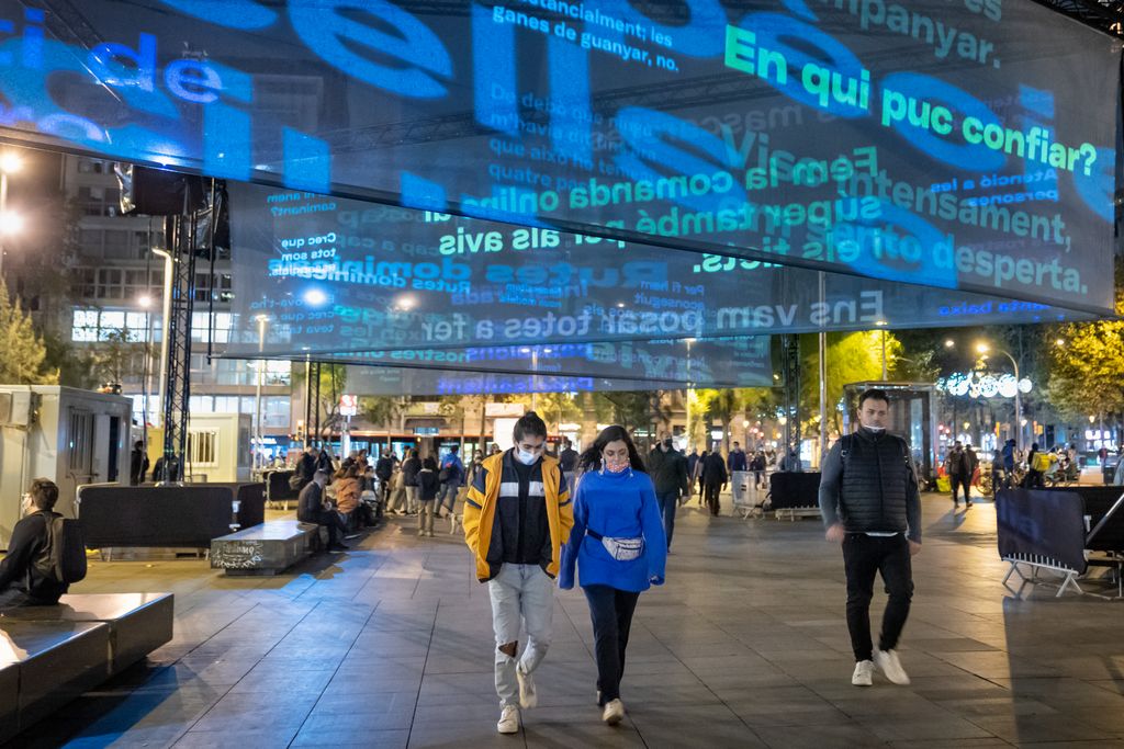 Gent caminant sota els llums de Nadal encesos a la plaça de la Universitat