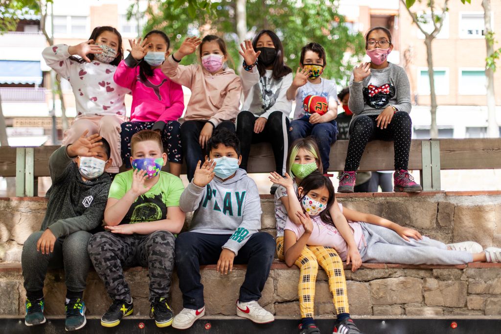 Nens de l'Escola Mercè Rodoreda asseguts en uns esglaons de la plaça de Nou Barris