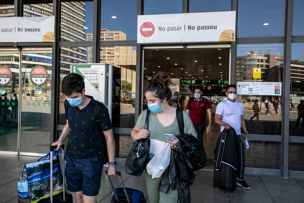 Gent amb maletes i bosses sortint de l'estació de Sants per la sortida de la plaça dels Països Catalans