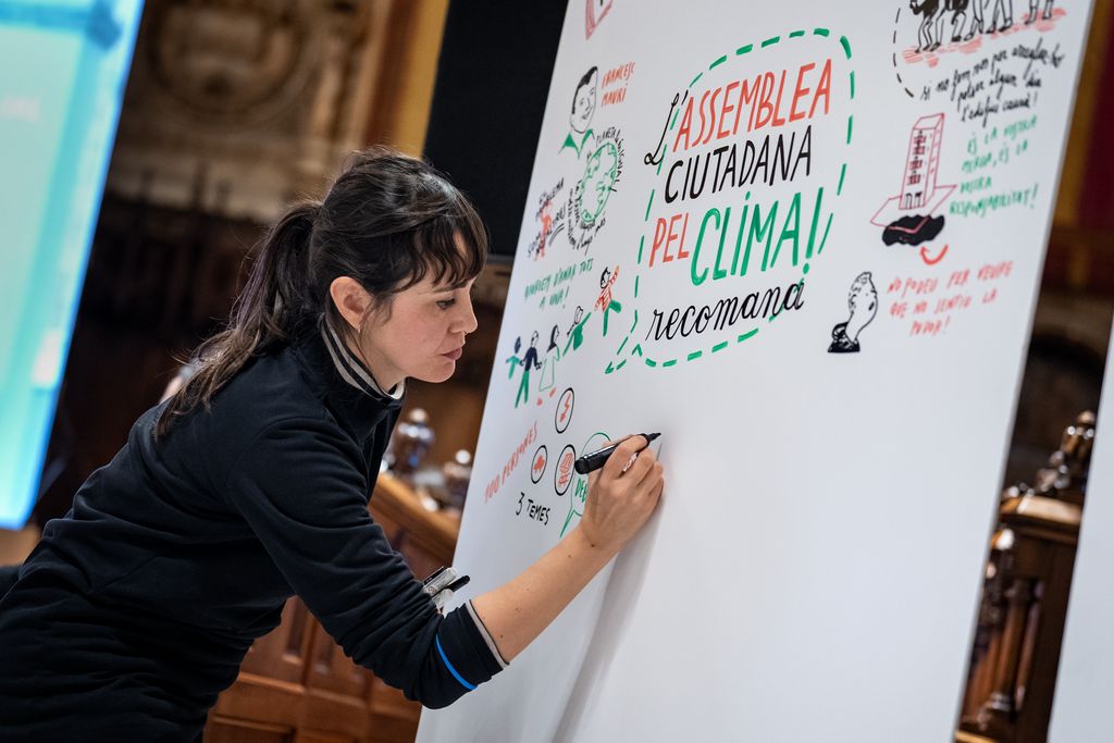Una chica hace diferentes dibujos durante las distintas intervenciones en las conclusiones de la Asamblea para el Clima, en el Saló de Cent del Ayuntamiento de Barcelona.