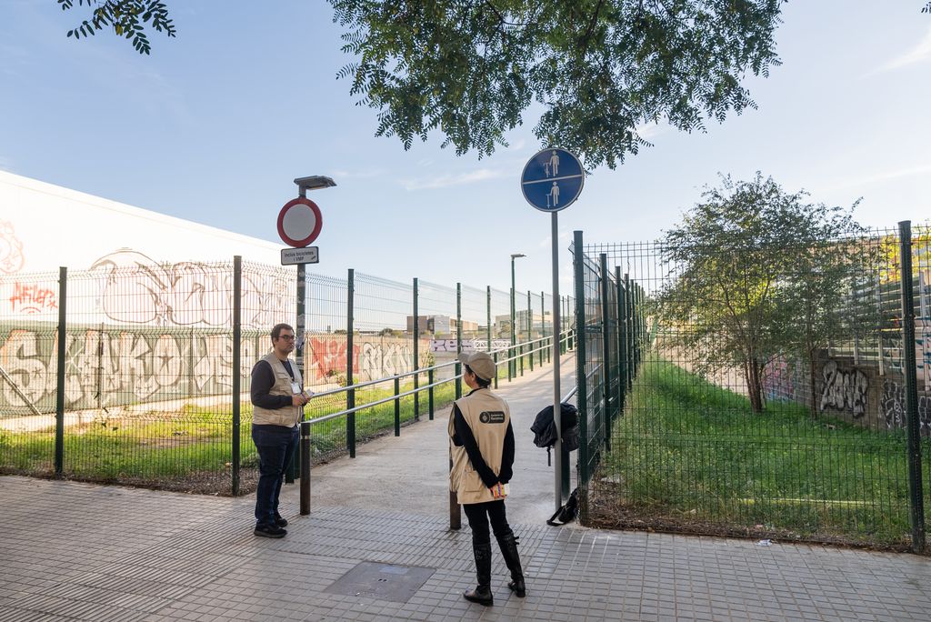 Dos informadors de l’Ajuntament de Barcelona davant la nova senyalització “Baixa de la bici i del patinet” col·locada al carrer Fernando Pessoa amb Joan Comorera