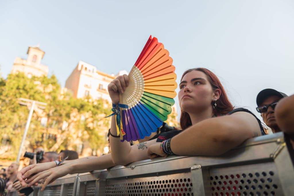 Una mujer abanicándose con un abanico de la bandera LGTBIQ+ en el pregón del Pride Barcelona 2025