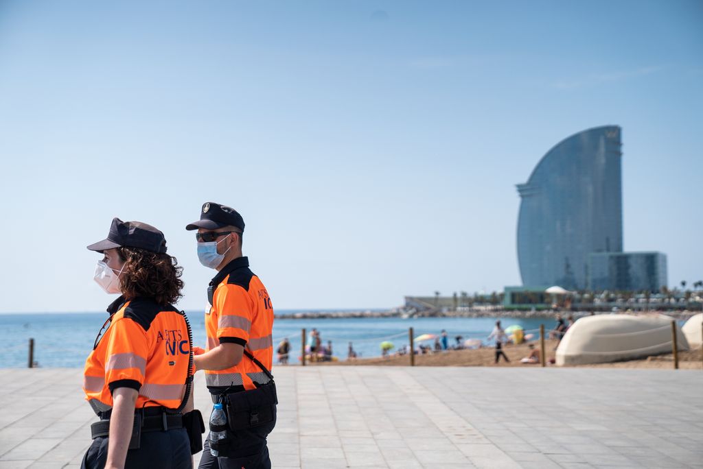 Una parella d'agents cívics patrulla pel passeig Marítim amb l'hotel Vela al fons