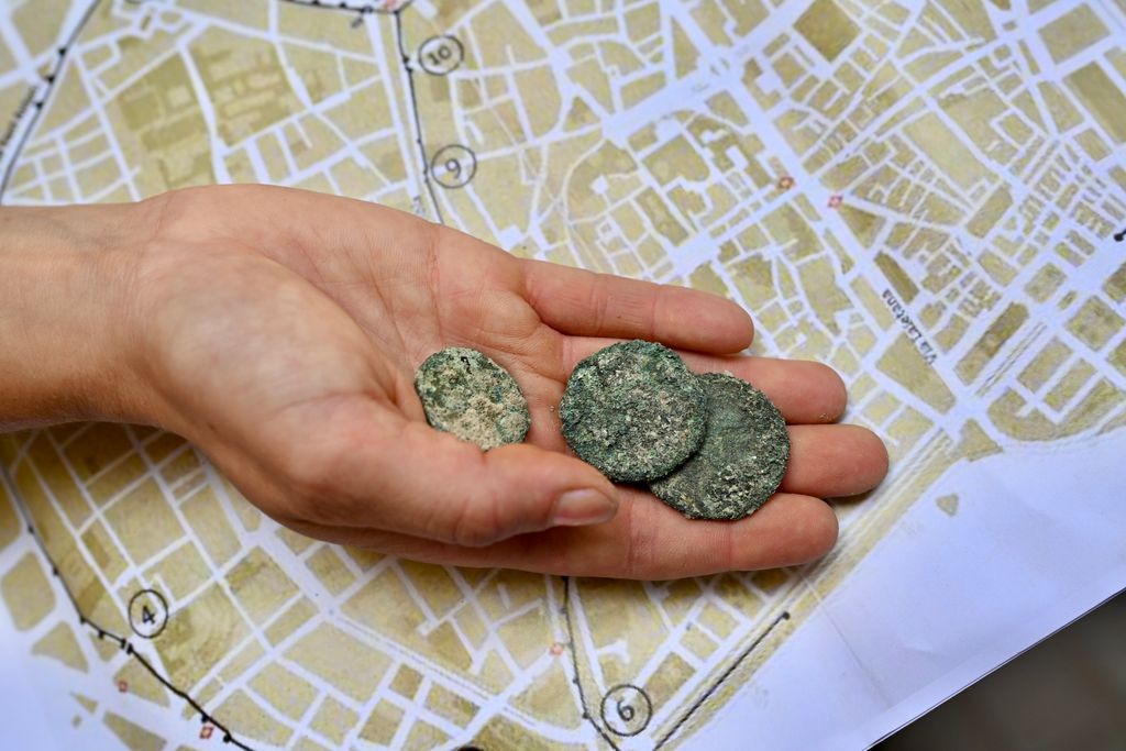 Un arqueòleg mostra unes monedes trobades durant les excavacions a la Rambla on s'ha trobat un tram de muralla i un portal d'entrada a l'actual plaça del Teatre, davant del Teatre Principal