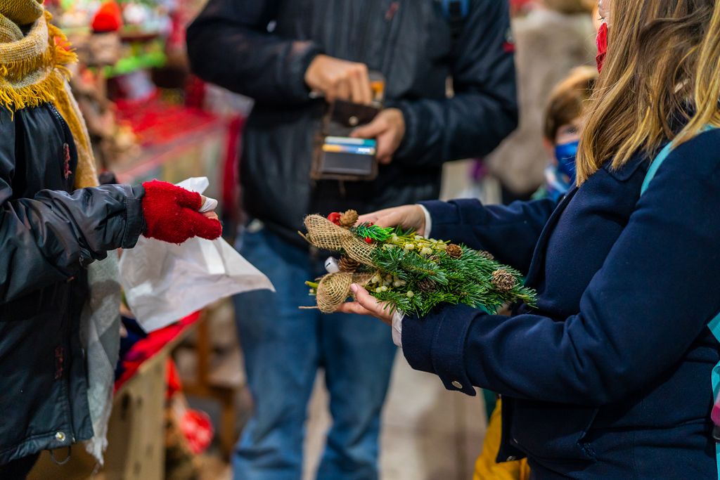 Una dona compra branques de vesc com a decoració nadalenca en una parada de la Fira de Santa Llúcia