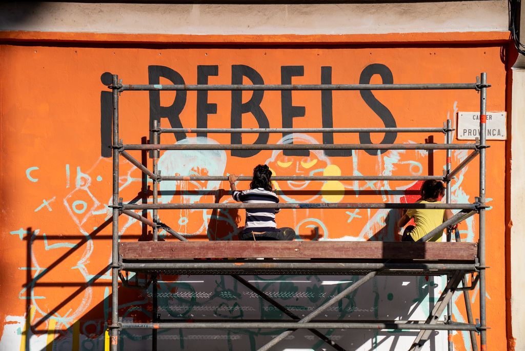 Dues de les il·lustradores del projecte del mural reivindicatiu feminista de la Model pinten una de les parts pujades a una bastida