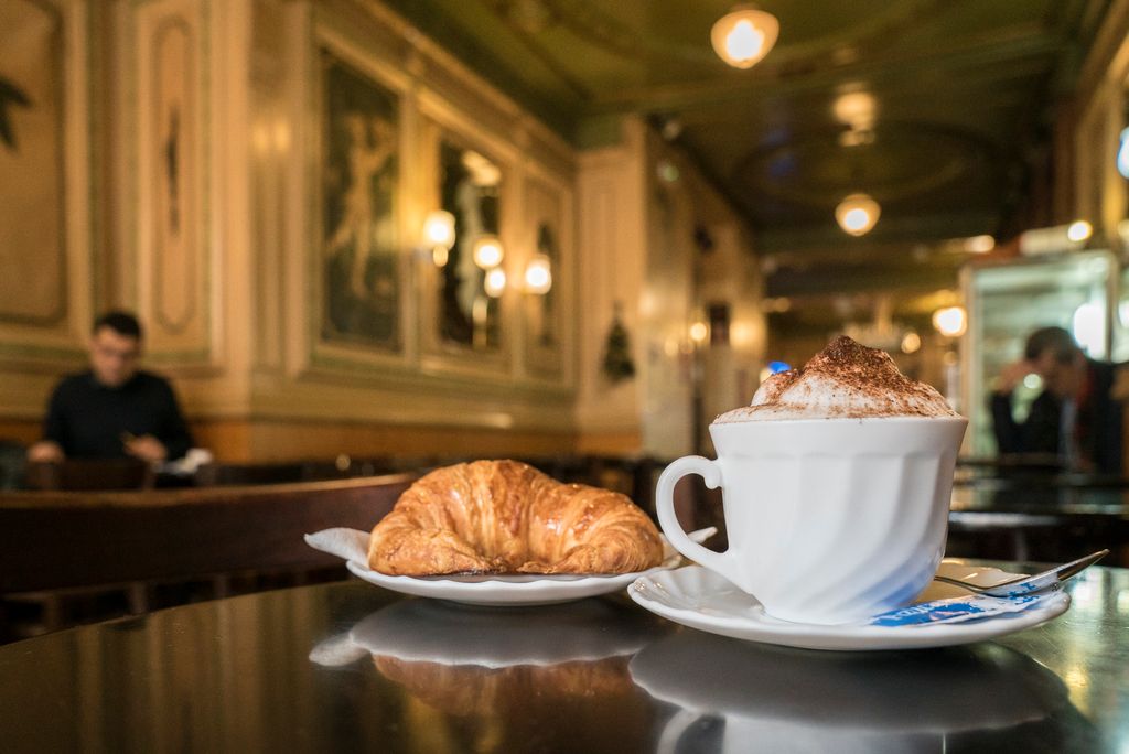 Esmorzar a una taula de la cafeteria amb un croissant i un capuccino