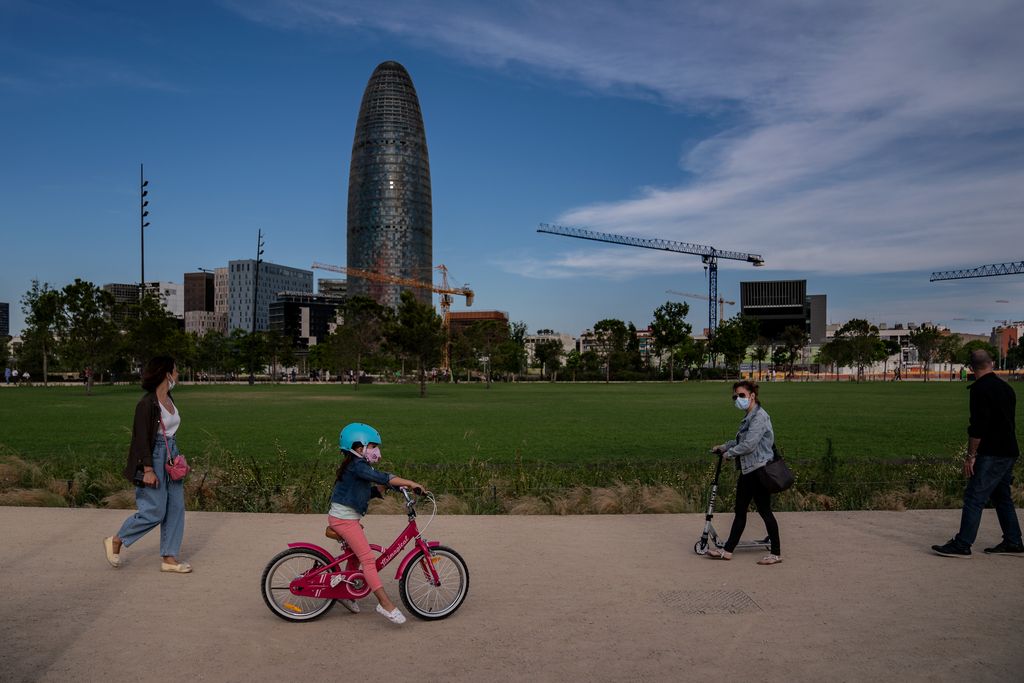 Gente paseando por el parque de las Glòries, entre ellos, una niña en bicicleta y una mujer con monopatín
