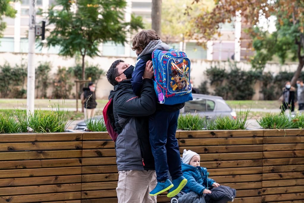 Un pare agafa en braços el seu infant a la sortida del col·legi, a la zona pacificada de vorera ampliada davant de l’Escola Sagrat Cor Ribes