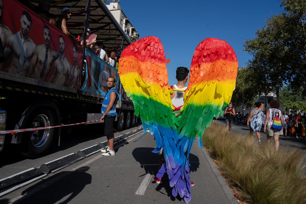 Una persona amb unes ales amb els colors de la bandera LGTBI durant la manifestació del Pride! 2023.