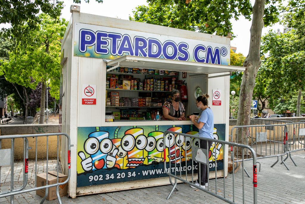 Una dona compra focs artificials i petards per a la revetlla de Sant Joan en un quiosc a la via Júlia