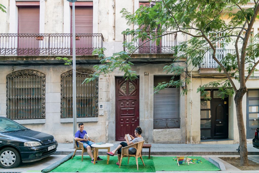 Joves llegint a una taula i jocs per a nens i nenes en la instal·lació del carrer Tapioles durant el Parking Day