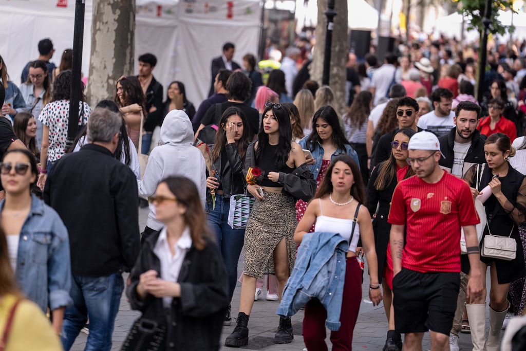 Persones passejant pel lateral del passeig de Gràcia amb les parades de Sant Jordi al centre de la via, que formen part de la superilla literària.