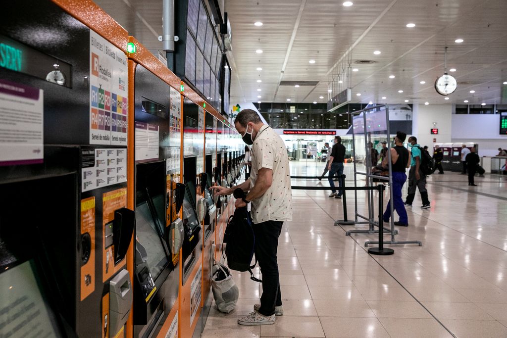 Vestíbul de l'estació de Sants on una persona compra el bitllet en una de les màquines expenedores