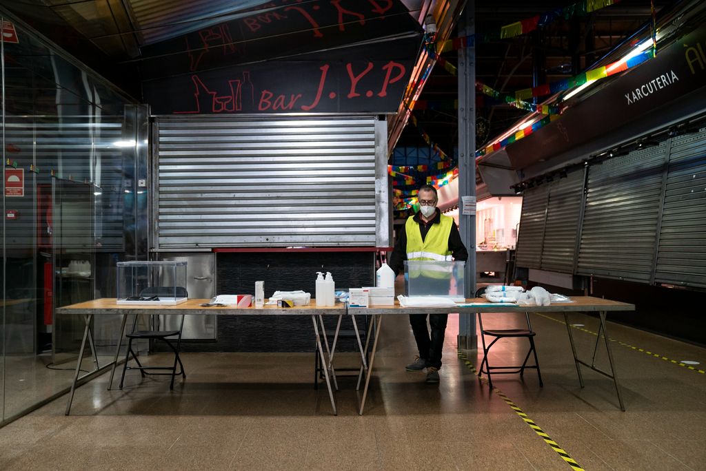 Un treballador municipal col·loca sobre les taules els diferents materials per a les meses electorals