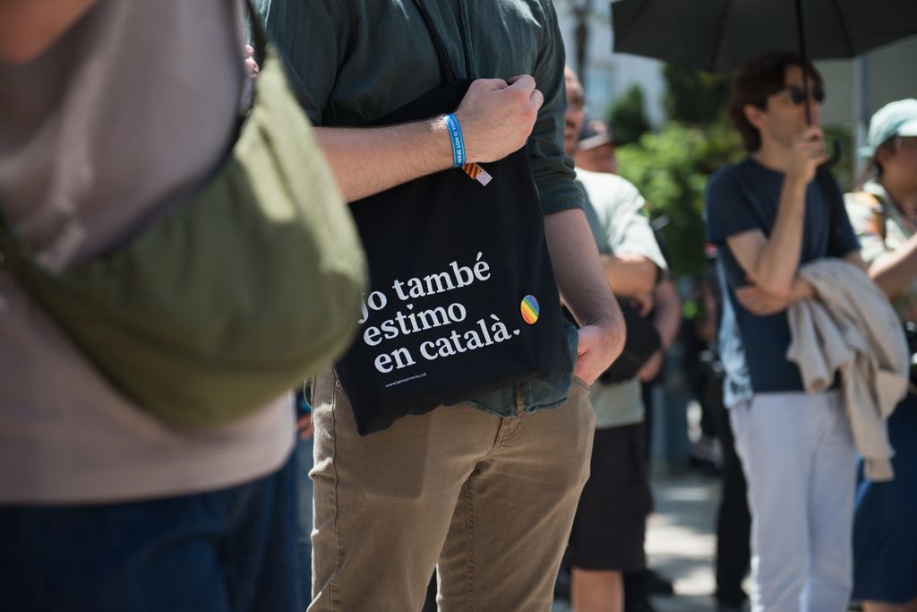 Un jove porta una bossa en què es llegeix “Jo també estimo en català” a l’acte d’inauguració del faristol en memòria de la primera manifestació LGTBI.