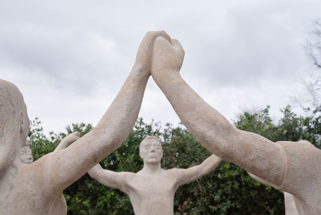 Detall dels braços i mans entrellaçats d'unes de les figures del monument a la Sardana un cop finalitzada la restauració