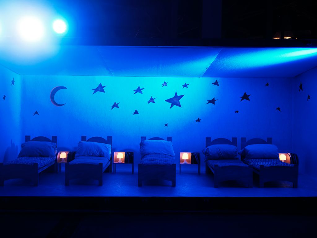 Habitació amb cinc llits petits al Parc de la Màgia de Nadal. A les parets s'hi veuen les estrelles i la lluna