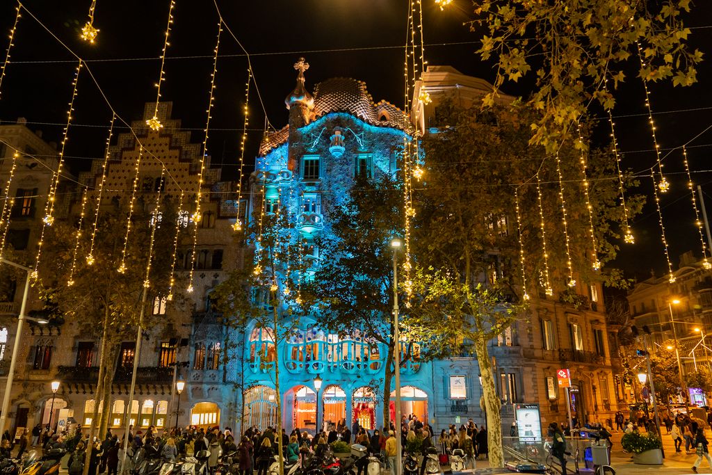 Casa Batlló amb la façana il·luminada de blau, amb els llums de Nadal del carrer encesos