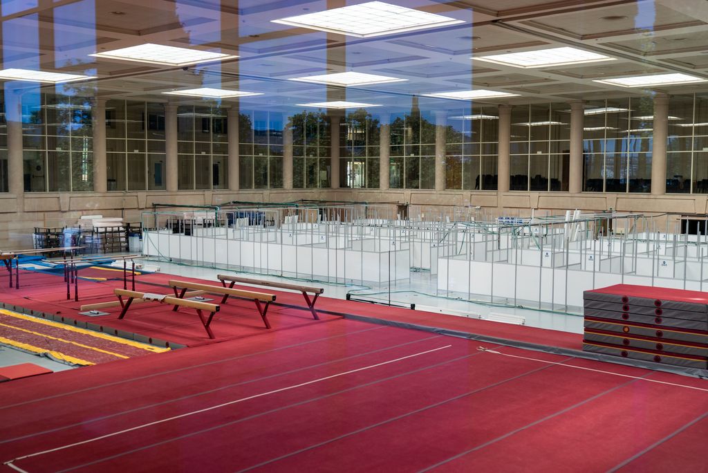 Vista d'una gran sala on l'emplafonat del Pavelló Salut de l'INEFC comparteix espai amb les barres d'equilibri, paral·leles i la superfície dels exercicis de terra