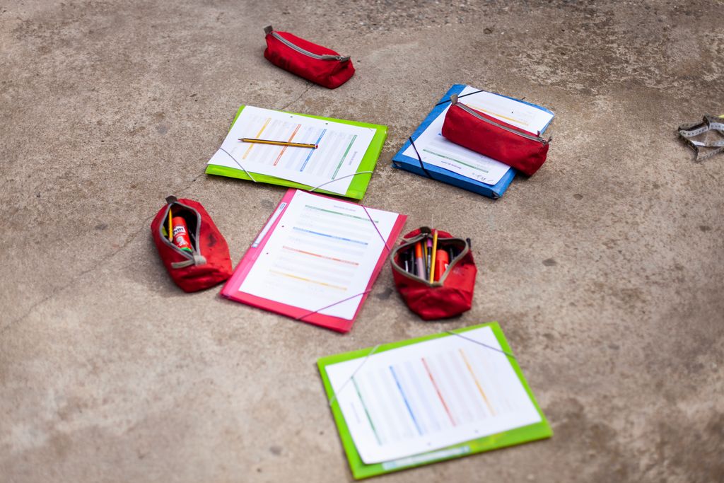 Carpetes amb fulls i estoigs al terra de la plaça de Nou Barris on els nens de l'Escola Mercè Rodoreda hi fan algunes de les classes