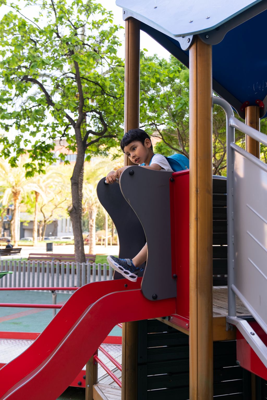 Un niño se desliza por un tobogán en la zona de juegos infantiles de los Jardines de Elx