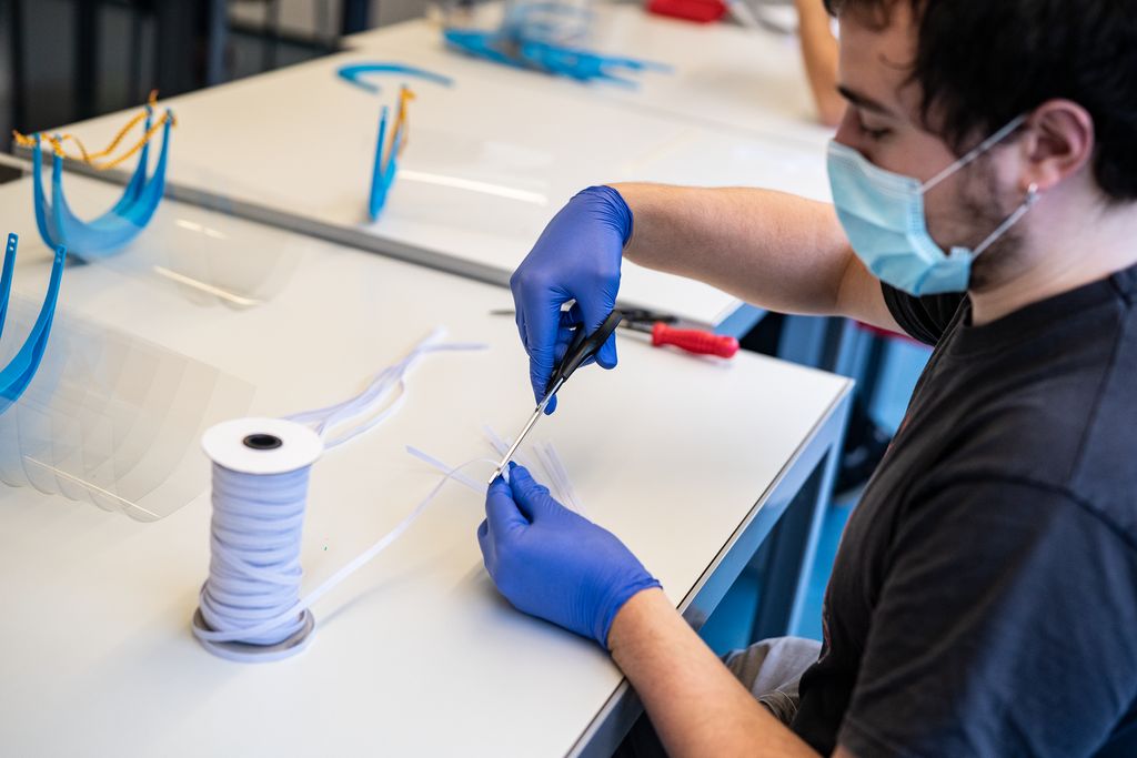 Un home amb mascareta talla goma elàstica per a les viseres al Parc Tecnològic Barcelona Activa.