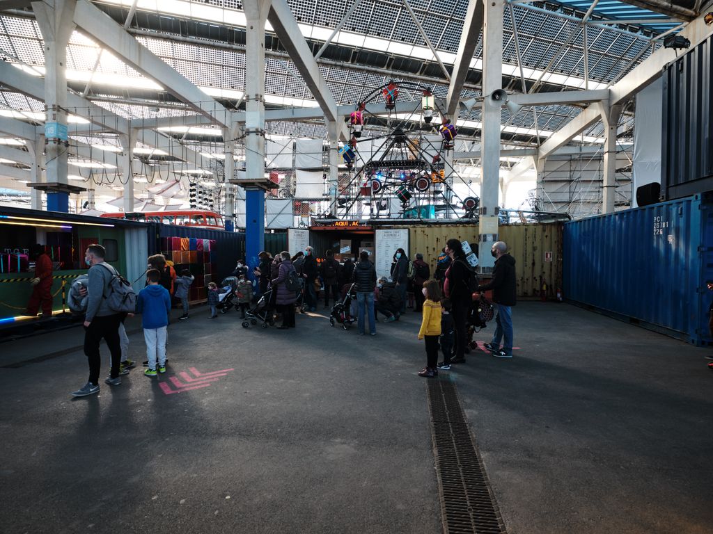 Famílies en una àrea del Parc de la Màgia de Nadal on es troba una gran roda de fira amb regals