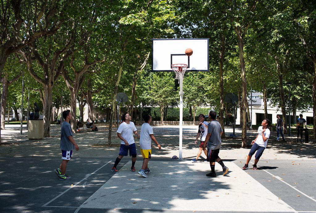 Homes jugant a la pista de bàsquet al Parc de l'Espanya Industrial