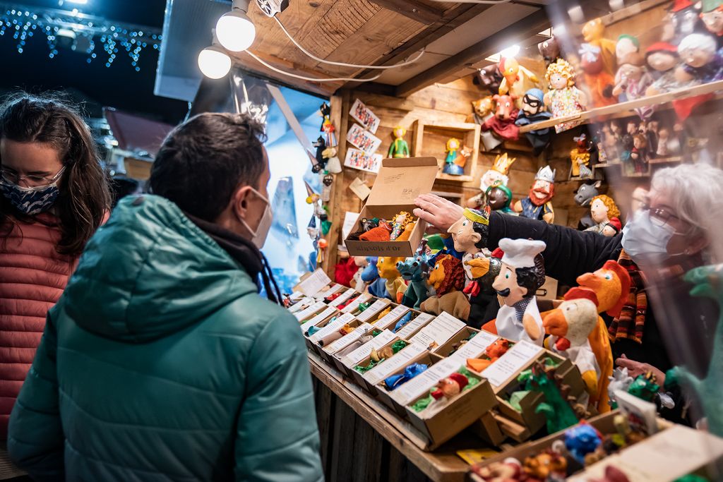 Una paradista mostra una capsa amb figures de titelles a un dels compradors a la Fira de Santa Llúcia