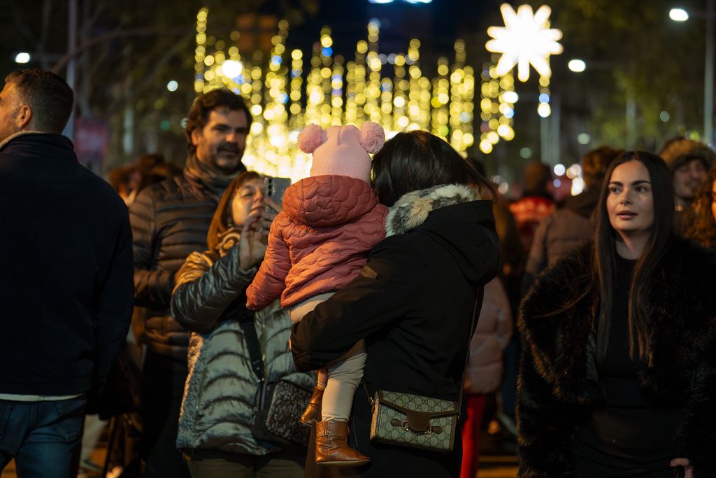 Gent passejant i mirant els llums de Nadal i un nen a collibè el dia de la prova de l'encesa de llums