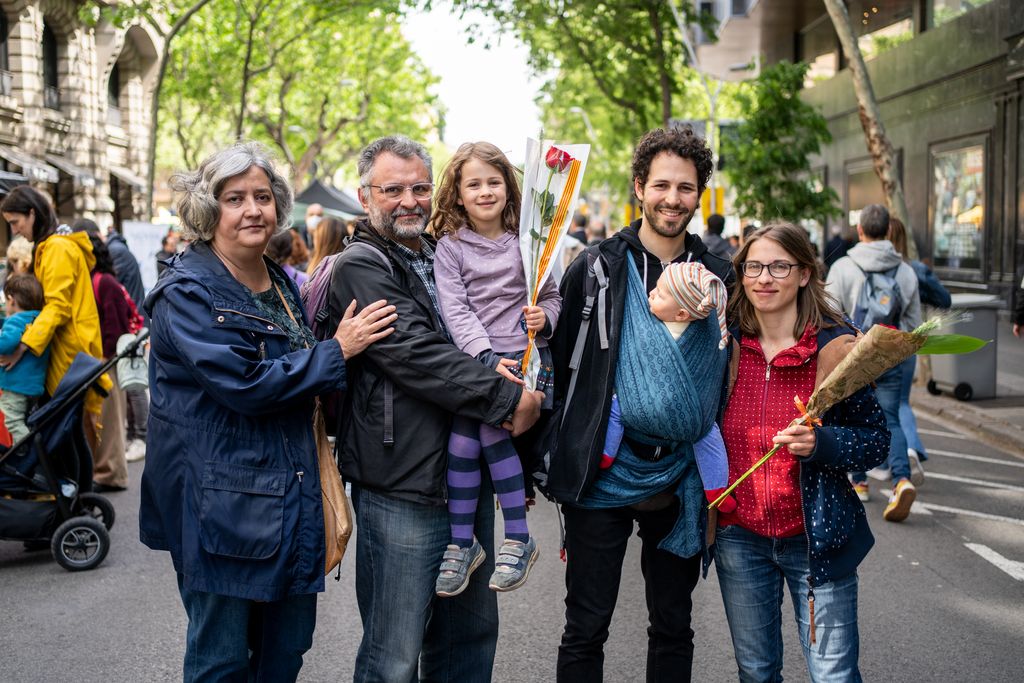 Una família amb membres de totes les edats passegen per la superilla literària de Sant Jordi i mostren les seves roses