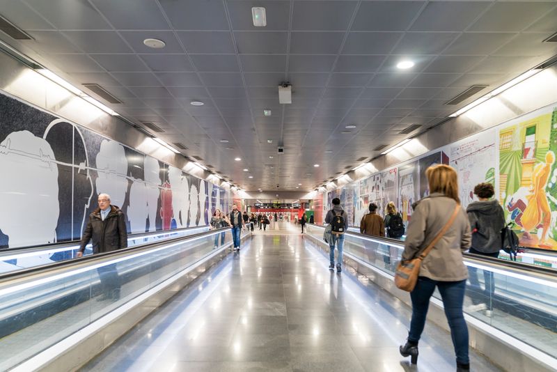
             Viatgers caminant per davant dels murals de l