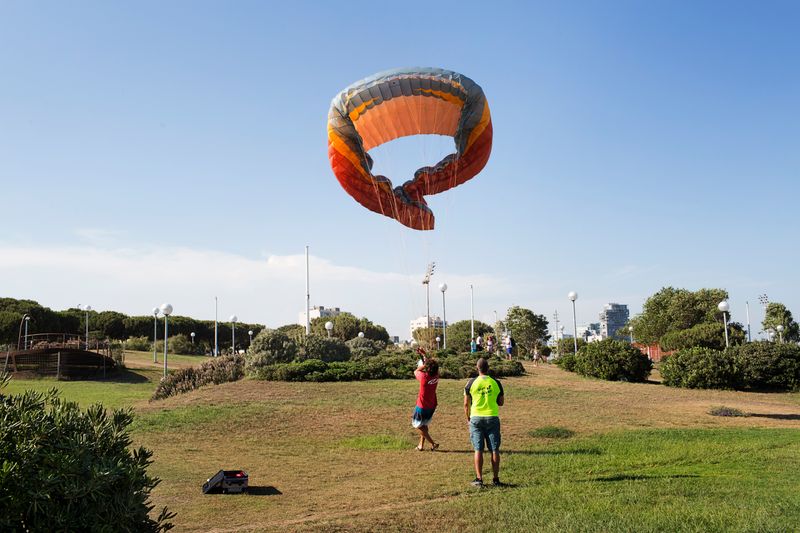 
             Homes jugant amb un parapent
             Autor: Paola de Grenet
             Mostra els detalls de la imatge Homes jugant amb un parapent
             