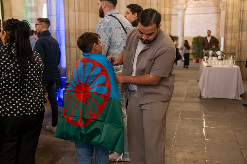 
             Un home lliga una bandera del poble gitano a un nen a l